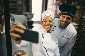 Wall Mural - Happy professional chefs have fun while taking selfie while working in restaurant.