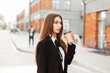 © alones - Business pretty woman in fashion black suit walks in the city and drinks coffee