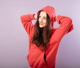 Canvas Print - Fun enjoying toothy smiling woman thinking and looking up  in fashion red hoodie on purple bright background with empty copy space.