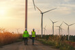© Pituk - Back view of young maintenance engineers team working in wind turbine farm at sunset.