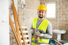 Portrait Of Skilled Maintenance Worker Holding Hammer Drill Perforator Standing At Indoor Building Site