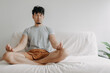 Asian man does meditation on the sofa with little distraction in his apartment.