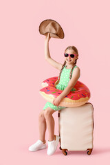 Poster - Happy little girl with suitcase, hat and inflatable ring on pink background