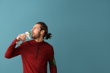 Poster - Sporty man drinking water on color background