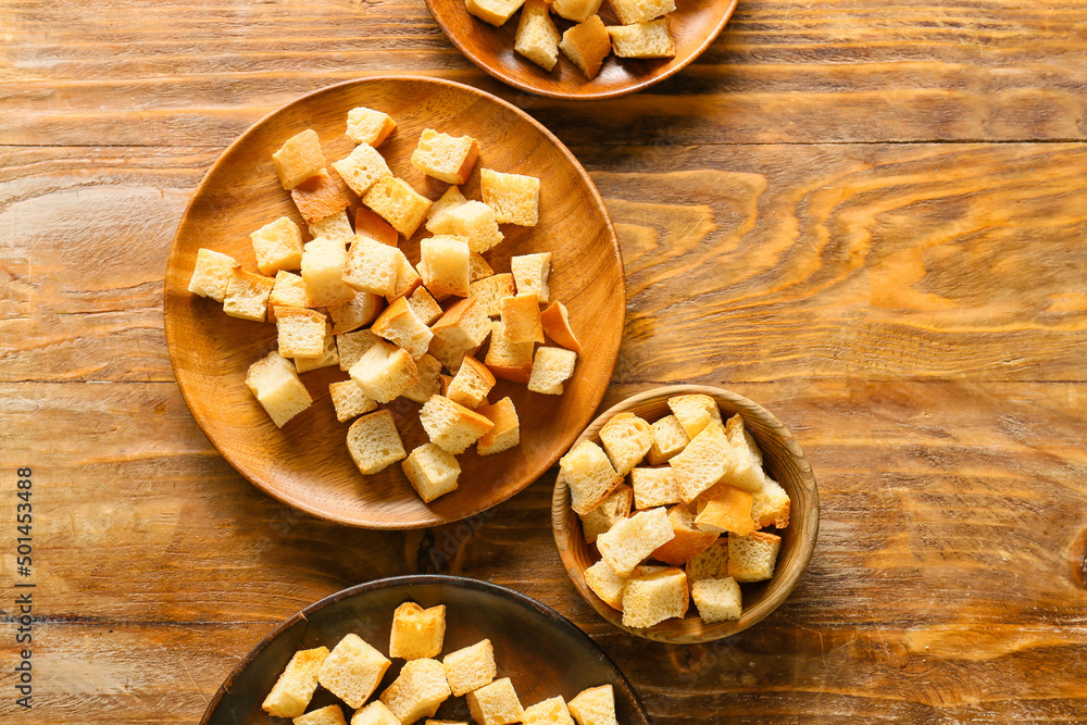 Bowls with tasty croutons on wooden background