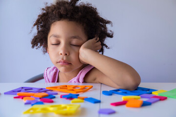 cute mixed race girl boring from of playing with educational toys and sleeping on table. preschool l