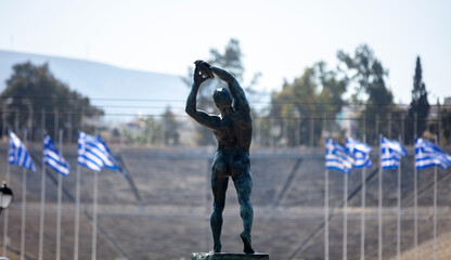 Athens, Greece. Discus thrower bronze statue, rear view. Panathenaic Stadium blur background