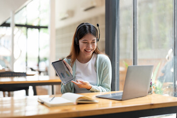 Wall Mural - Asian woman writing making list taking notes in notepad and digital tablet working or learning on laptop indoors- educational course or training, seminar, education online concept