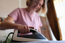 Woman Irons Clothes With Iron On Ironing Board