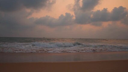 Wall Mural - Wide angle slow motion shot of Calangute beach during the sunset with clouds above the ocean at North Goa in Goa, India. Clouds above the sea waves with dramatic sky after the sunset. Beach Background