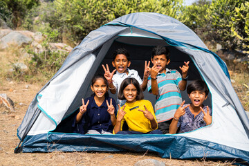 gorup of kids inside camping tent grimacing by looking at camera during summer camp of hill top - concpet of happiness, relaxing and vacation