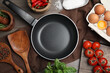 Flat lay composition with cooking utensils, frying pan and fresh ingredients on wooden table