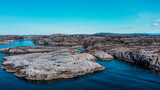 Fototapeta Na ścianę - Aerial view of the sea wave and rocks of the coastline of Norway, Telavåg. Panoramic view of the rocks by the sea. The sea wave rolls along the shore. View of the sea coast from the air. Ocean space