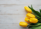 Fototapeta Tulipany - Delicate yellow tulips on white wooden background
