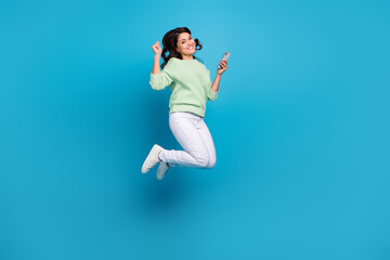 Sticker - Full length photo of cute young brunette lady jump with telephone wear shirt pants footwear isolated on blue background