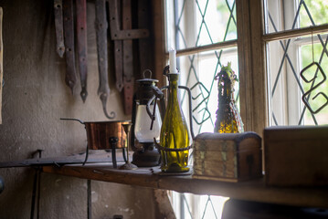 Wall Mural - Closeup shot of small chest boxes, candle bottle stand, and old gas lamp on the side of a window