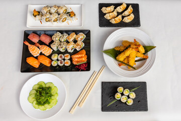 Wall Mural - Top view  of sushi set on black and white plates on a white background