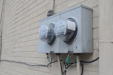 Selective focus shot of grey electricty meters on a white brick wall