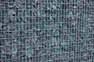 Poster - texture of a gray metal mesh fence and pieces of green glass on the street