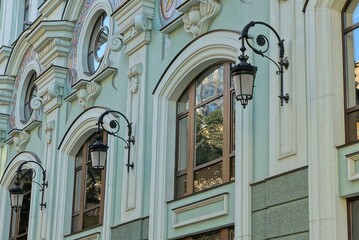 Wall Mural - a row of brown windows on the green stone wall of an old house with black lanterns on the street