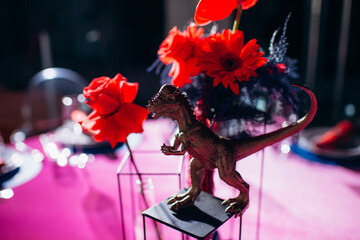 Wall Mural - unusual stylish decor on the festive table with red and blue flowers and dinosaurs