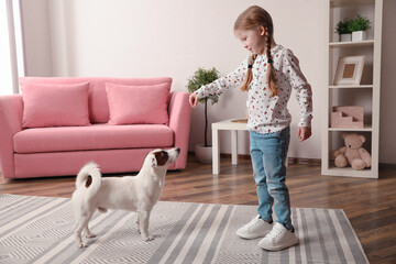 Wall Mural - Cute little girl feeding her dog at home. Childhood pet