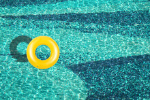 Aerial View Of Yellow Ring Float In A  Blue Swimming Pool Under Bright Sunny Day