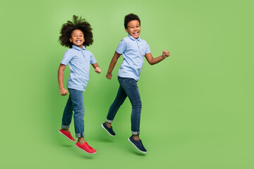 Wall Mural - Full length body size view of trendy cheerful pre-teen friends friendship jumping strolling isolated over green color background