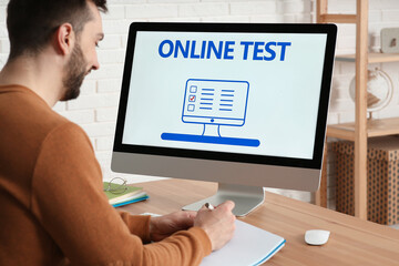 Wall Mural - Man taking online test on computer at desk indoors