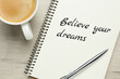 © New Africa - Motivational quote Believe Your Dreams written in notebook on wooden table, flat lay