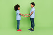 © deagreez - Full length body size view of attractive nice cheerful trendy kind pre-teen kids holding hands isolated on green color background