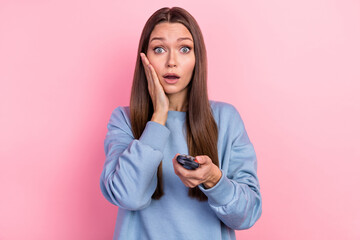 Poster - Portrait of attractive stunned girl watching scary movie switch channel isolated over pink pastel color background