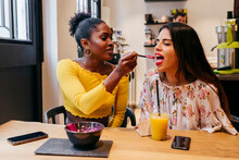 Woman Feeding Friend With Smoothie