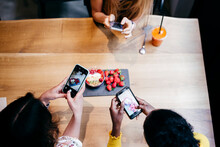 Women Taking Pictures Of Healthy Food In Cafe
