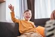 Overjoyed boy with genetic disorder sitting at the sofa and laughing out loud