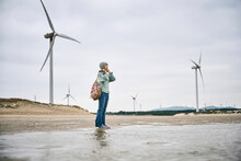 Woman Stand Near Windmills On Seaside