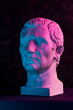 Blue purple gypsum copy of ancient statue of Guy Julius Caesar Octavian Augustus head for artists on dark textured background. Renaissance epoch. Plaster sculpture of man face.Template for art design