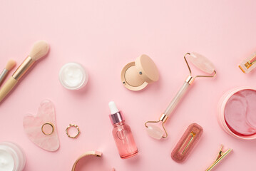 Wall Mural - Top view photo of makeup brushes rose quartz roller gua sha pink eye patches glass transparent bottle cream jars eyeshadow barrettes lip gloss gold rings and wristlet on isolated pink background