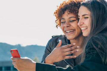 smiling girls looking at mobile phone in the street