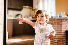 Funny Toddler Girl Dancing Indoors, Little Child Play, Baby Having Fun Moving And Jumping On The Floor In A Sunny White Room, Kitchen At Home Or Kindergarten.