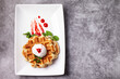 Homemade freshly baked belgian waffles with mascarpone, mint leaves and strawberry sauce
