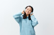 © SHOTPRIME STUDIO - Cheerful pretty Korean young female in blue hoodie headphones listen fav song look aside posing isolated on over white studio background. The best offer for ad. Music App Platform Ad concept