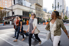 Mature Women Friends With Suitcases Crossing City Street At Crosswalk