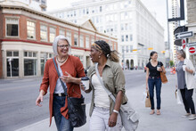 Mature Women Friends Walking And Talking In City