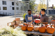 Male Plant Shop Owner Helping Customer With Pumpkins