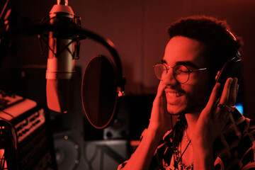 Poster - Portrait of young African American singer working in recording studio standing in front of microphone with pop filter enjoying singing