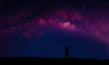 Fototapeta Kosmos - A person standing happily beside the Milky Way Galaxy pointing to a bright star.