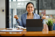 Excited Executive Receiving Good News Online Sitting In A Coffee Shop, Business Success. Asian Businesswoman Celebrating Victory At Work. Free Space