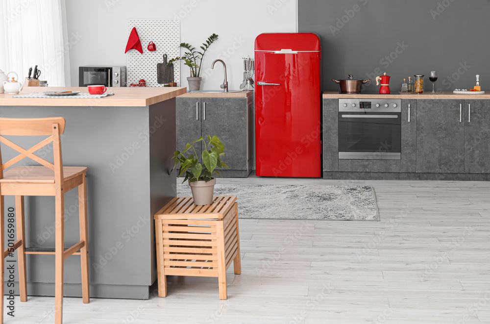 Interior of modern kitchen with red fridge, counters and pegboard