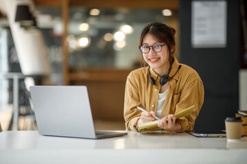 Student learning on laptop indoors- educational course or training, seminar, education online concept, Asian woman with modern laptop and headphones learning at home
